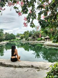 Rear view of woman sitting by lake