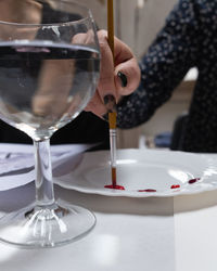 Midsection of woman holding wine glass on table