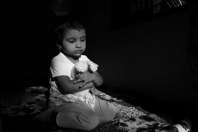 Cute girl looking away while sitting on bed