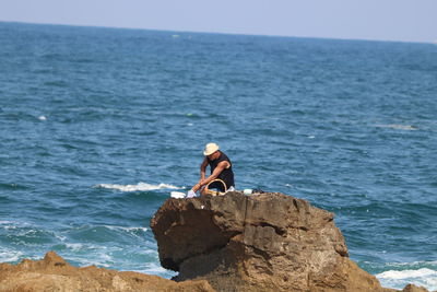 Rocks on rock by sea against sky