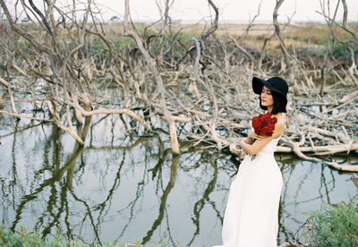 Side view of young woman standing by plants