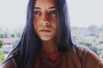 Close-up of thoughtful young woman looking away while standing against clear sky