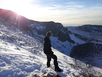 Rear view of man standing on mountain against sky during sunset