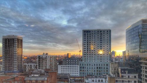 Modern buildings in city against sky during sunset