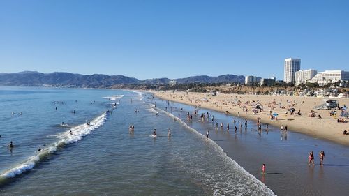 Group of people on beach against clear sky