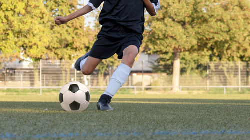 Low section of soccer player kicking ball on playing field