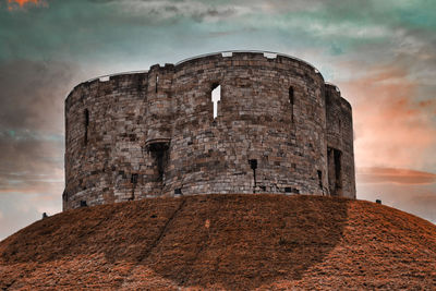 Low angle view of fort against cloudy sky