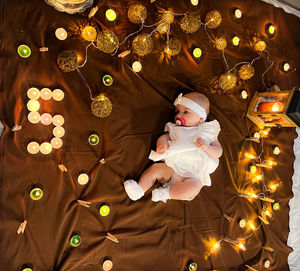 Cute girl lying down on illuminated bed