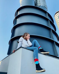 Low angle view of woman sitting against sky