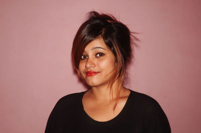 Portrait of young woman standing against wall