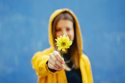 Smiling woman with flower standing against blue background