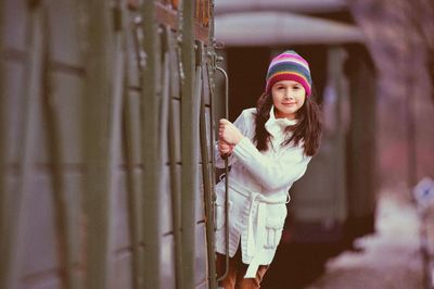 Portrait of girl wearing coat standing on train during winter