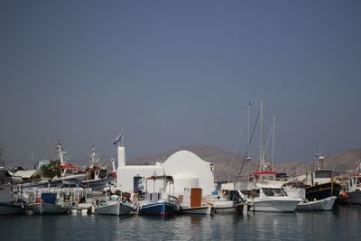 Boats moored at harbor against clear sky