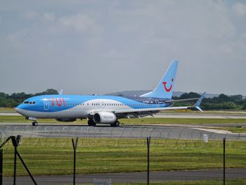 Airplane on airport runway against sky