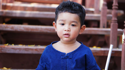 Close-up of cute baby boy with steel stick on staircase