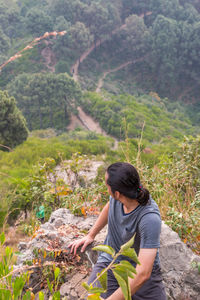 Man sitting on rock against trees in forest