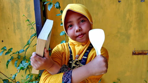 Portrait of girl holding spatula and cookbook