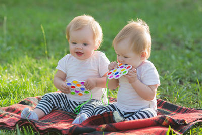 Cute baby girls sitting on field