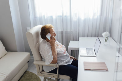 Senior woman talking on smart phone at home