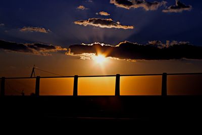 Silhouette railing against sky during sunset