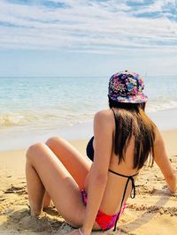 Young woman in bikini on beach against sky