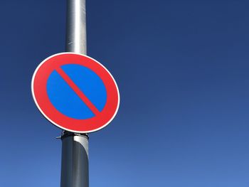 Low angle view of road sign against blue sky