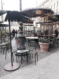 Chairs and tables at sidewalk cafe in city