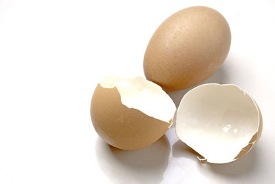 Close-up of broken egg against white background