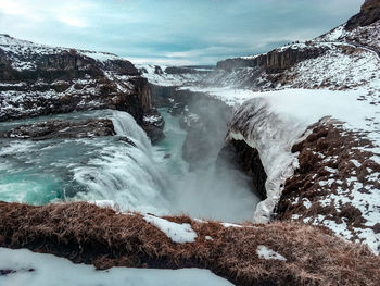 Scenic view of waterfall against sky during winter