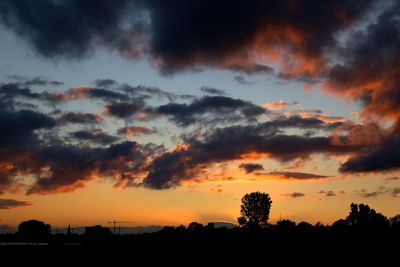 Silhouette trees against dramatic sky during sunset