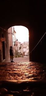 Rear view of man standing on street by buildings in city