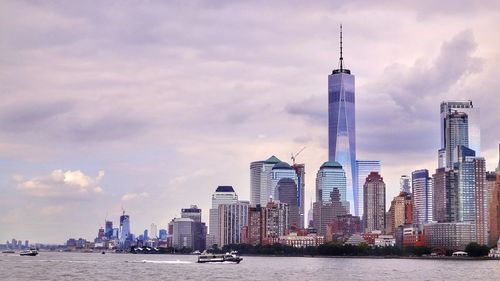 City at waterfront against cloudy sky