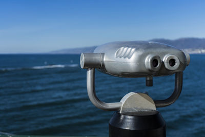 Close-up of coin-operated binoculars against sea and sky