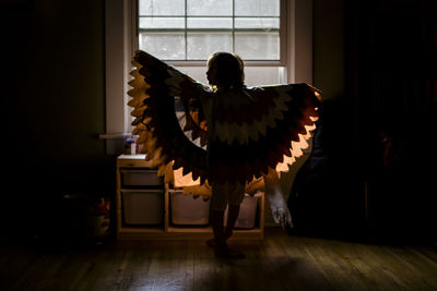 Rear view of woman standing by window at home