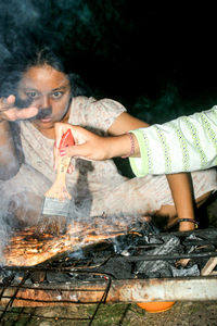 Portrait of woman with meat on barbecue grill