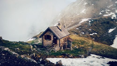 House on snow covered mountain against sky