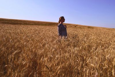 Side view of woman standing on field against clear sky