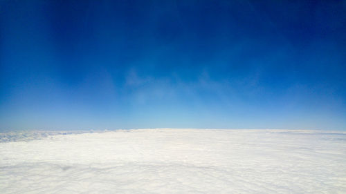 Low angle view of snow covered landscape against blue sky