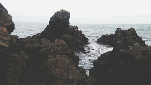 Rock formation in sea against clear sky