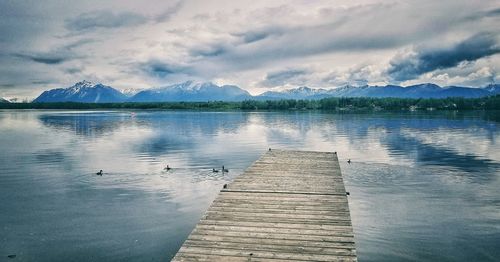 View of pier over lake against cloudy sky