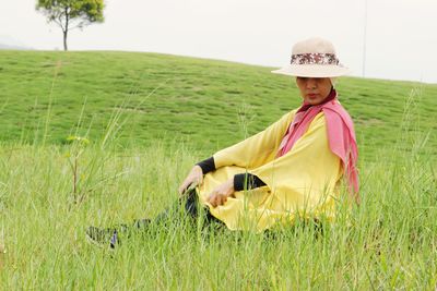 Side view of woman with hat standing on field
