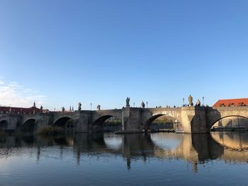 Arch bridge over river against clear blue sky