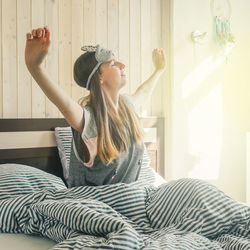 Young woman sitting on bed at home