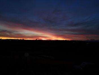 Silhouette landscape against dramatic sky during sunset