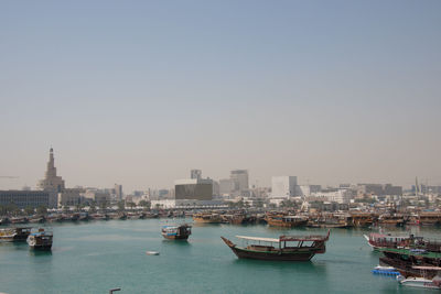 Boats moored in sea by buildings against clear sky