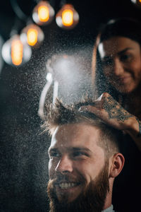 Hairdresser spraying water on man hair at salon