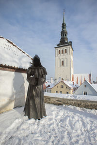 People in front of building against sky during winter