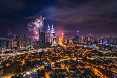 Firework display over illuminated buildings in city at night