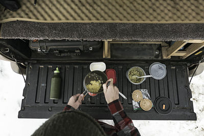 Overhead view of woman preparing food at trunk of off-road vehicle