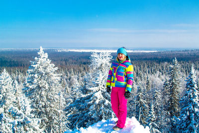 Full length of young woman standing on snow covered mountain against landscape